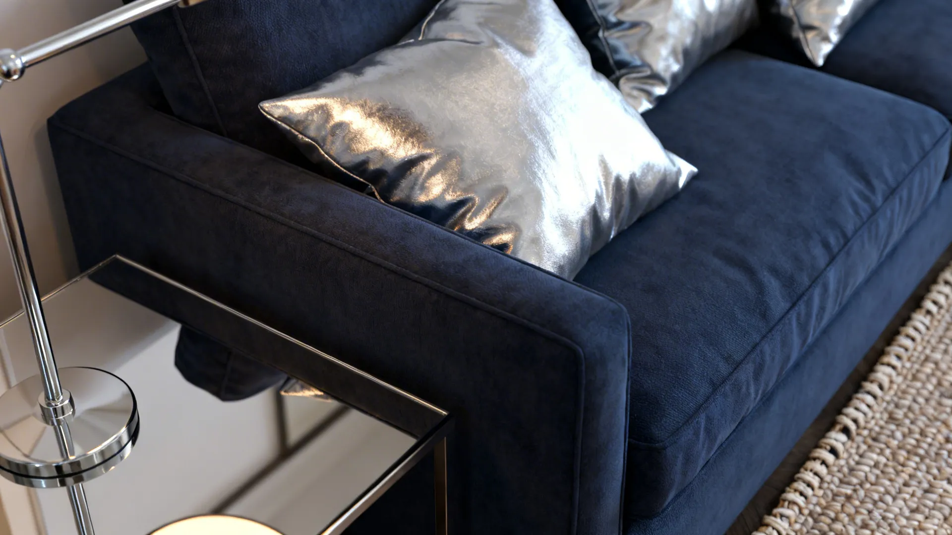 Close-up of navy sofa with silver pillows and mirrored coffee table reflecting light.