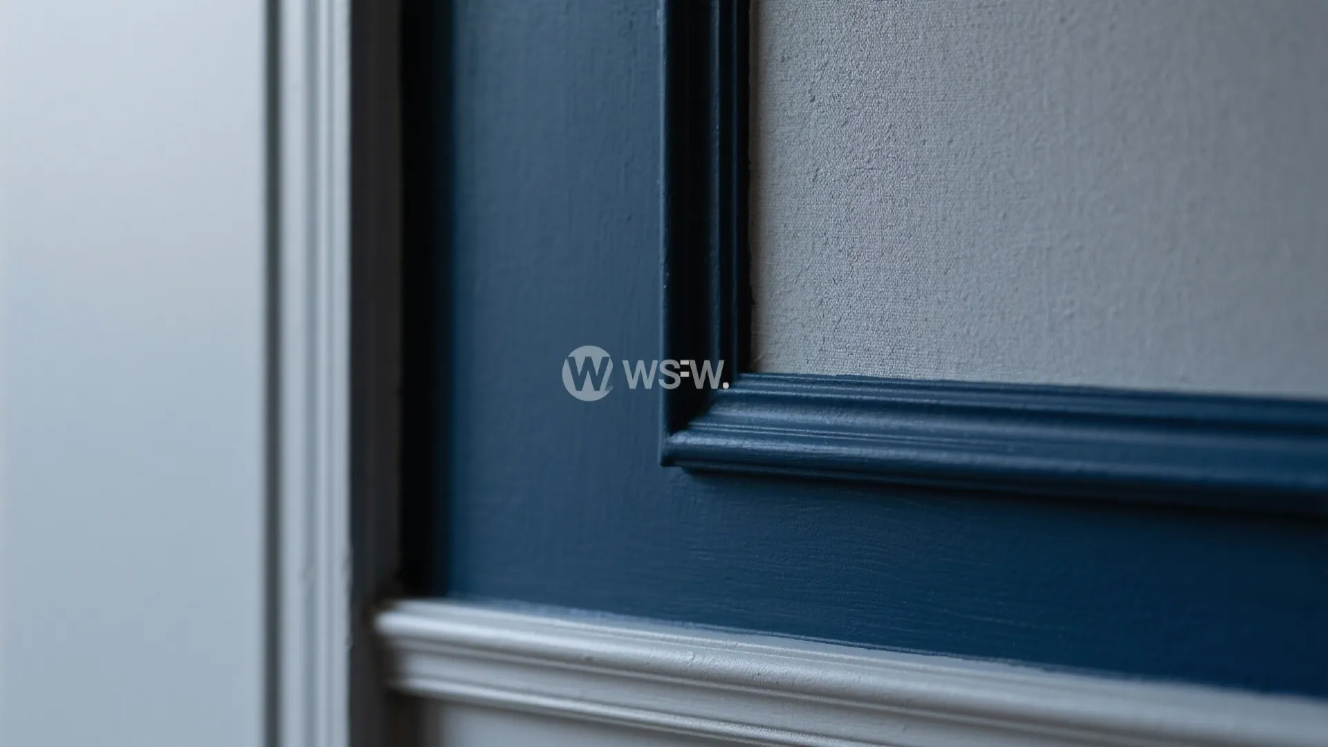 Close up of blue wall panel with decorative molding detail and white wall paint section