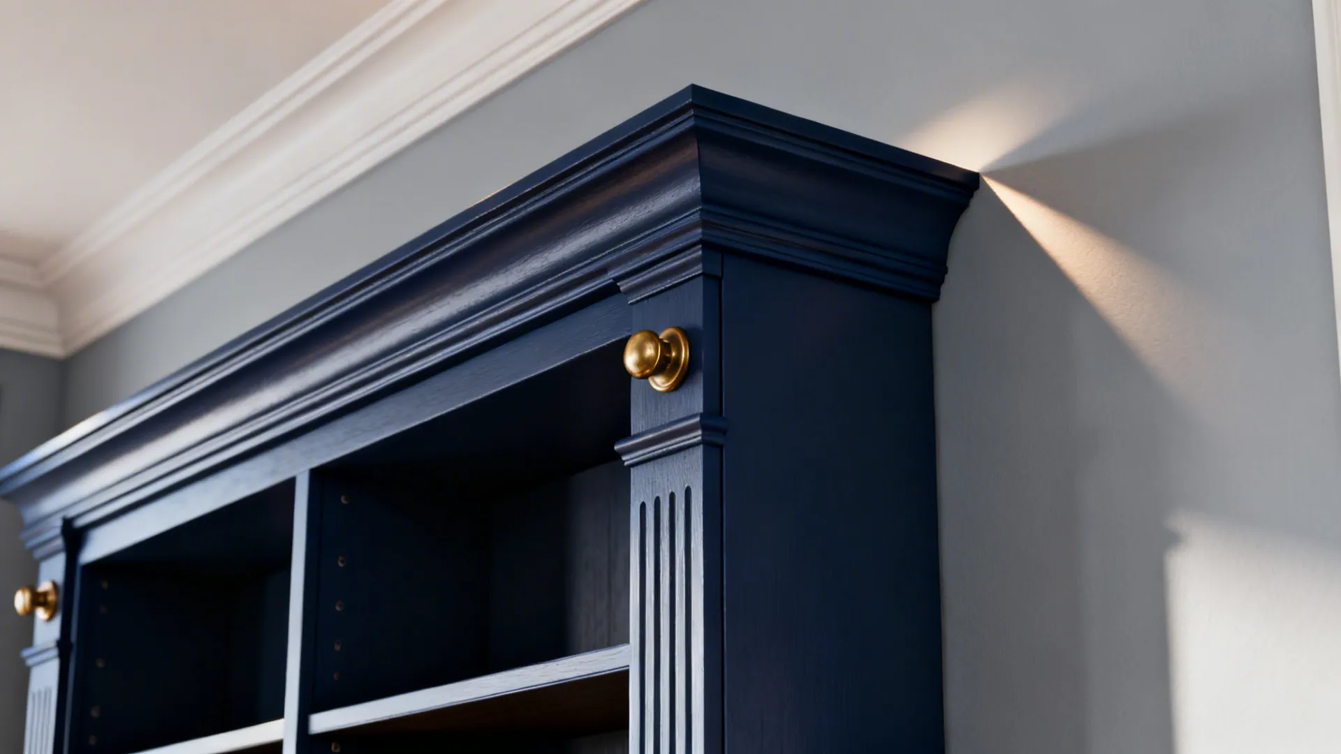 Close-up of navy trim and built-in shelving against pale grey walls with brass hardware.