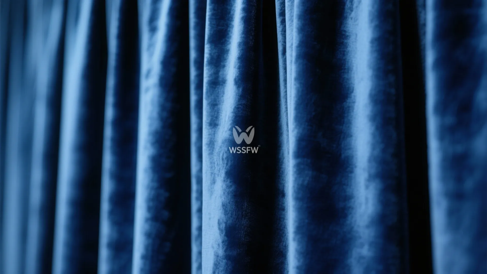 Close-up of soft navy blue velvet curtain fabric showing elegant vertical folds and smooth texture
