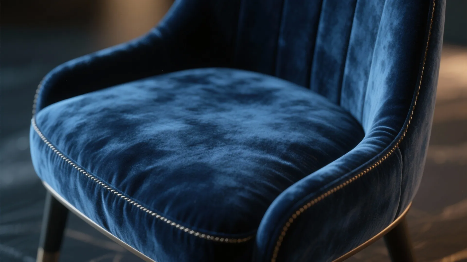 Close up view of a soft navy blue velvet sofa with elegant gold metal details