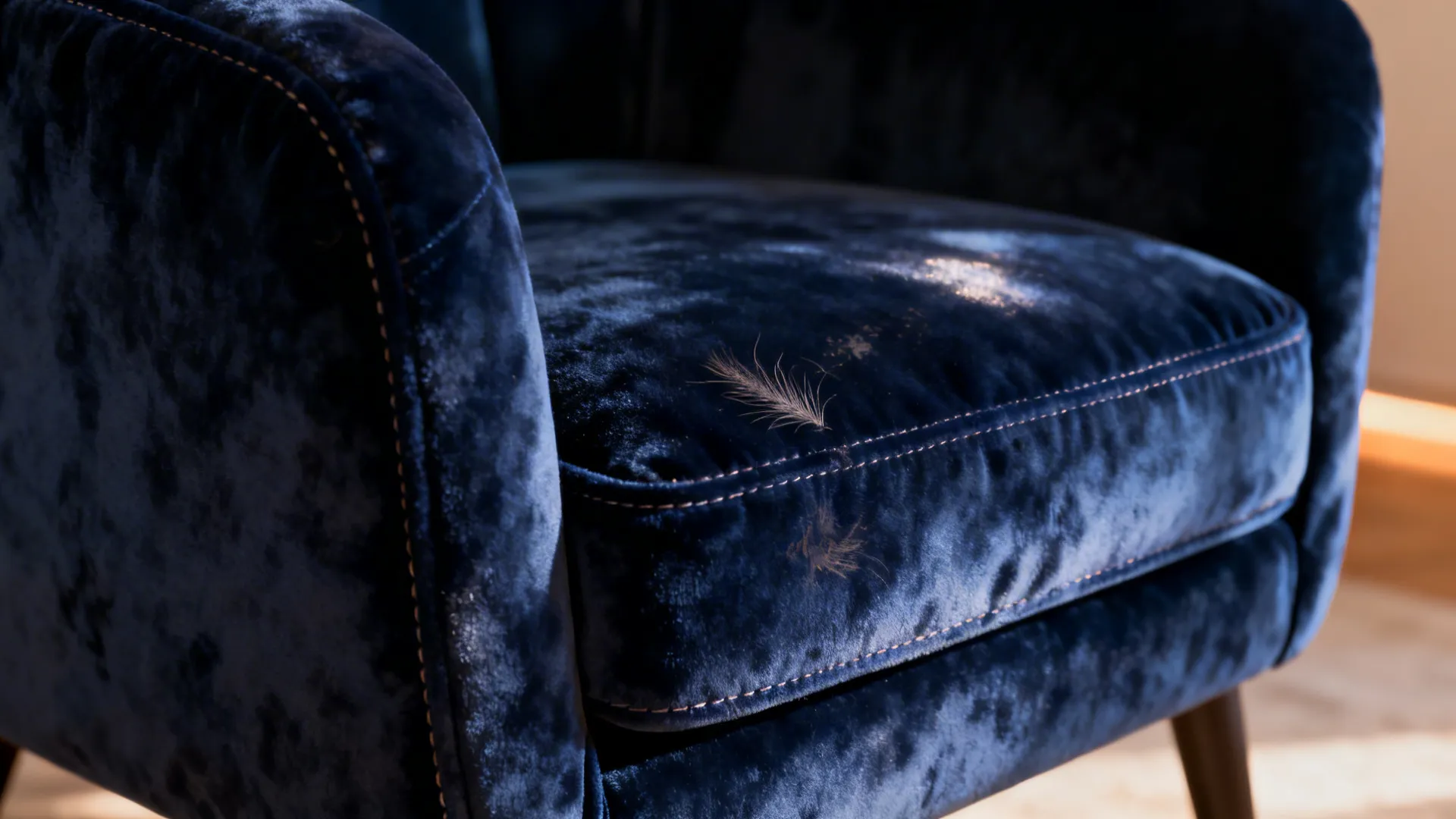 Macro close-up of deep navy velvet chair fabric showing texture and fine stitching.