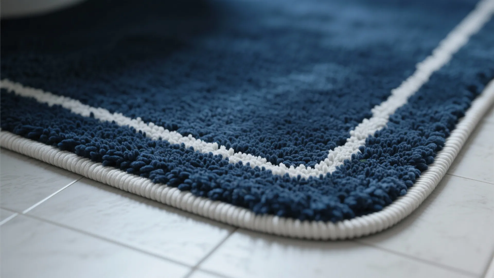 Close-up of a navy bathroom rug with crisp white piping showcasing texture and stitching.
