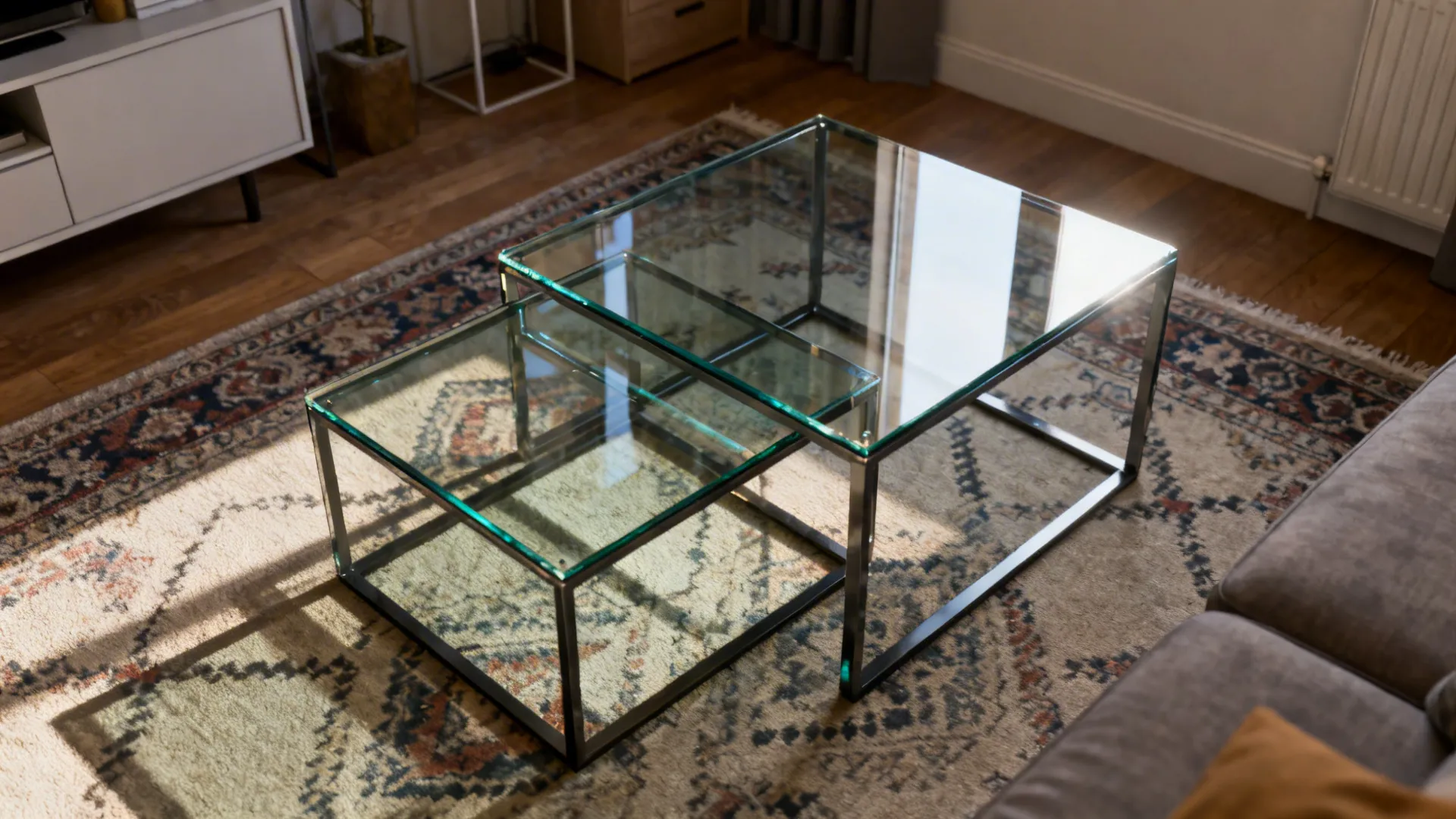 Top-down view of nested glass coffee tables staggered over a patterned rug in a small living area.