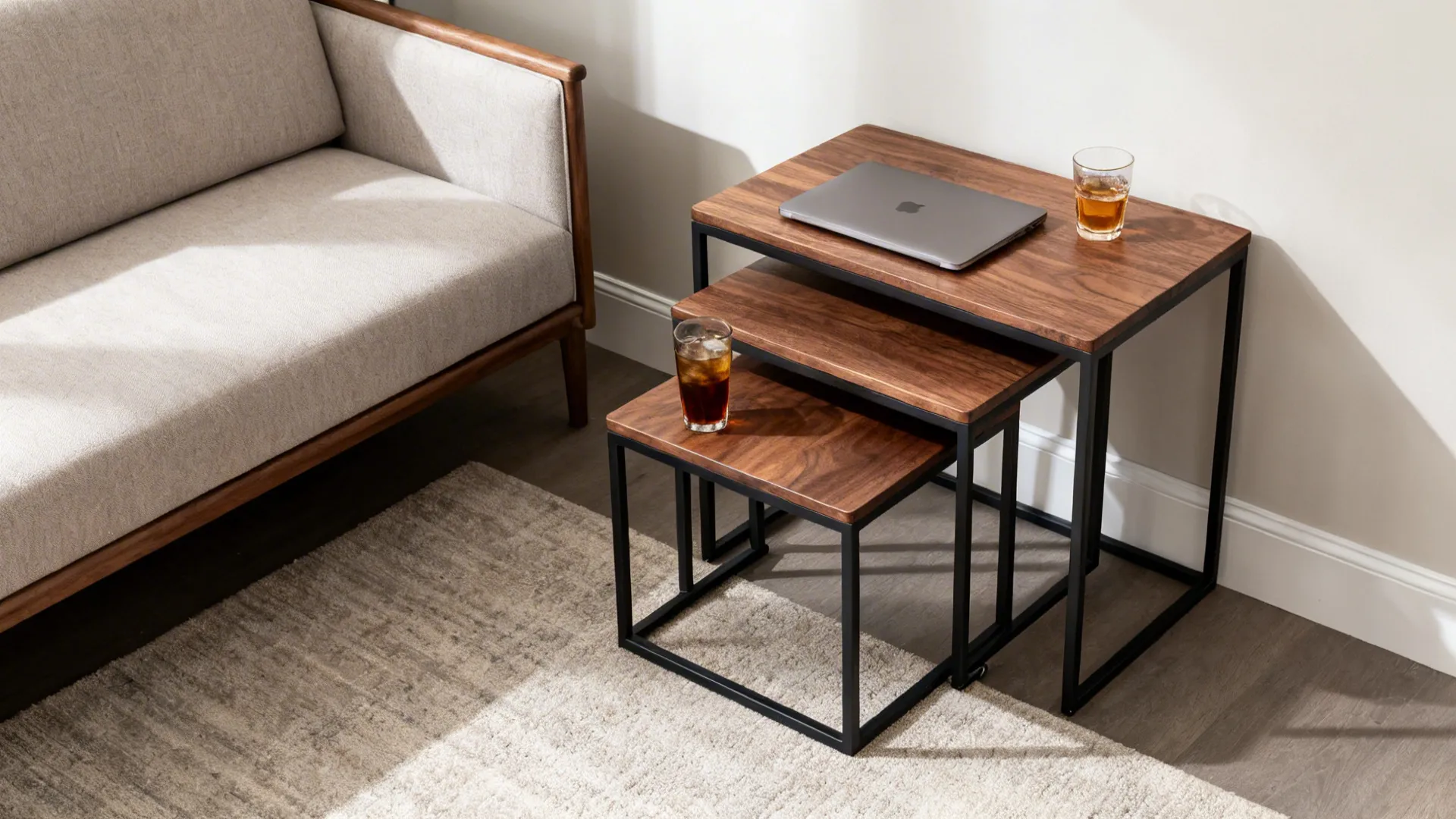 Walnut nesting tables in a small living room, one table pulled out to serve drinks and a laptop.