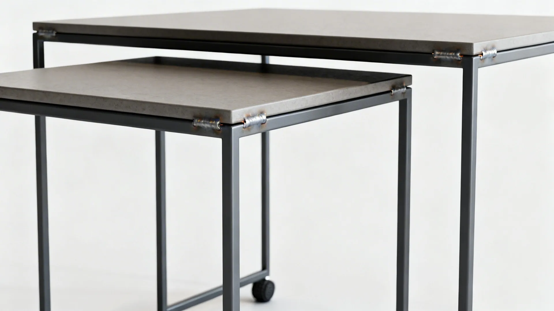 Close-up of slim metal-frame nesting tables showing welded joints and powder-coated finish.