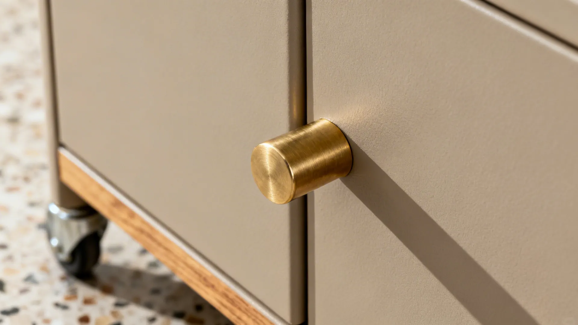 Macro of matte greige trolley finish with a brushed brass handle under soft daylight.