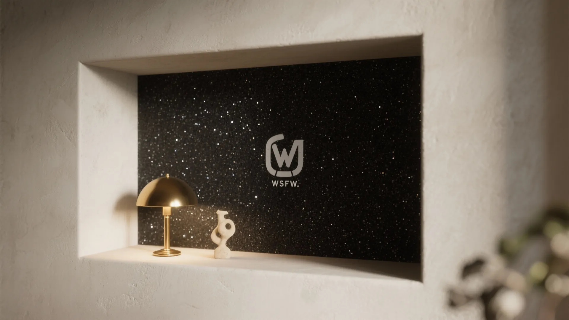Wall niche with black glitter background featuring gold table lamp and a small white sculpture