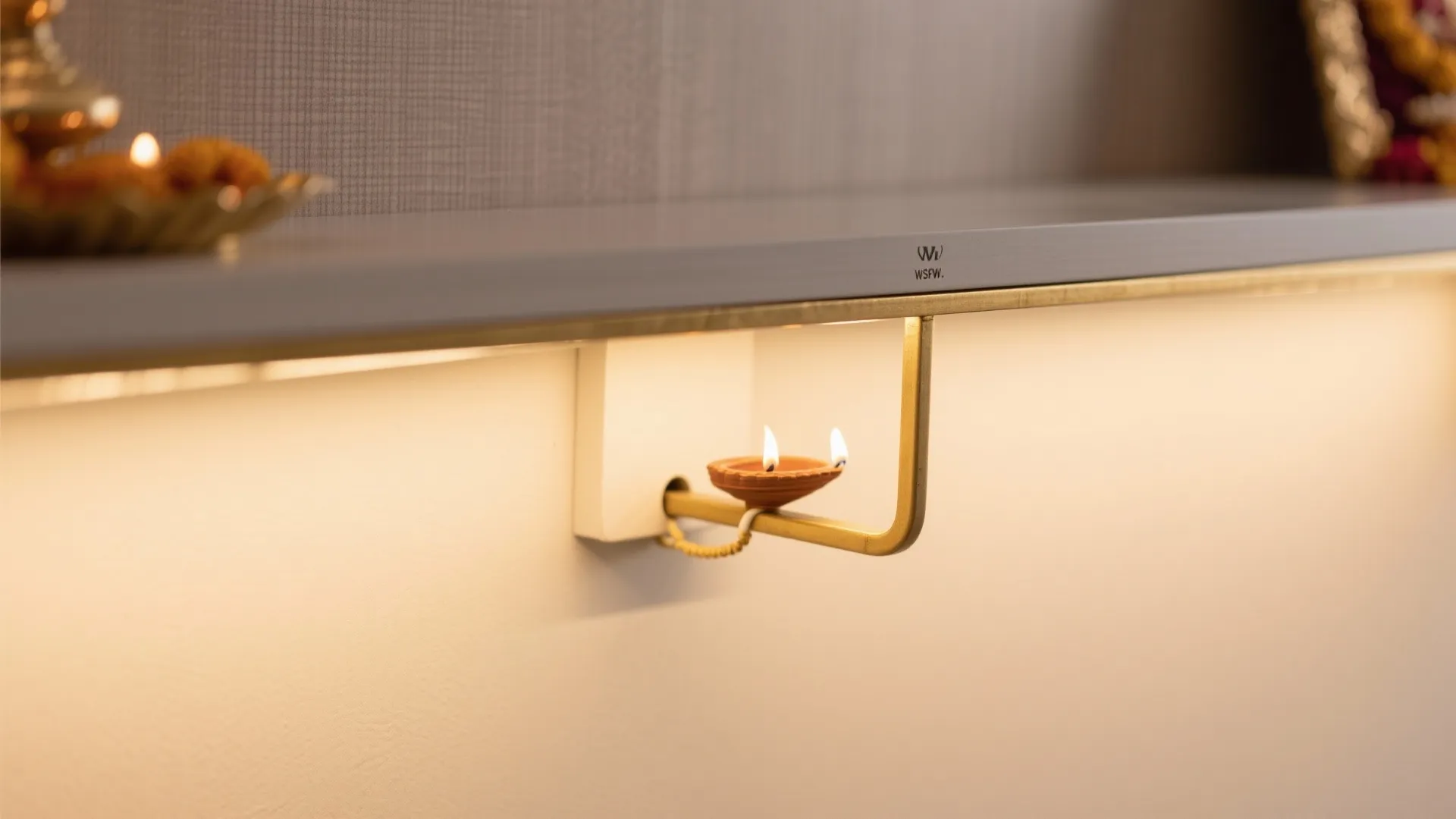 Close-up of brass trim and matte shelf finish on a wall-mounted pooja niche.