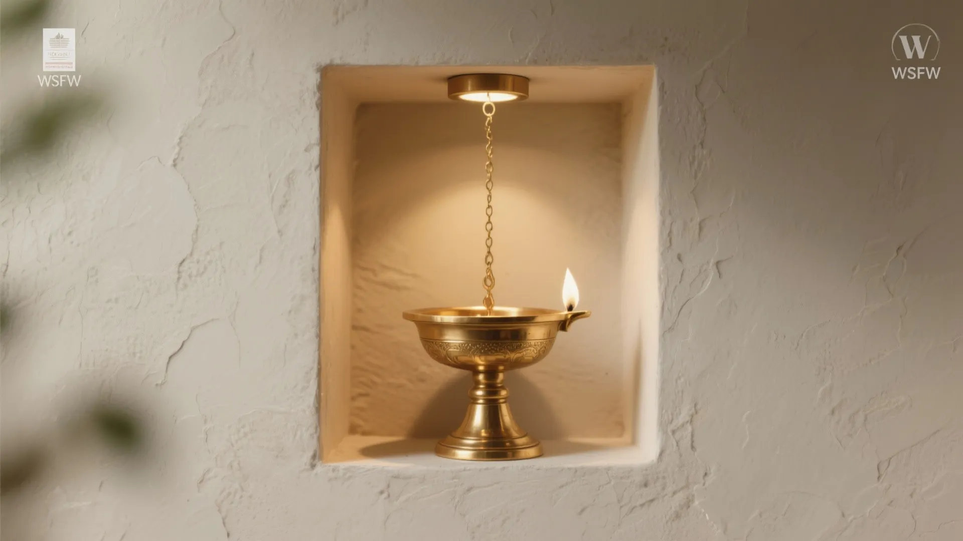 Brass oil lamp inside a wall niche with a gold chain and soft warm lighting