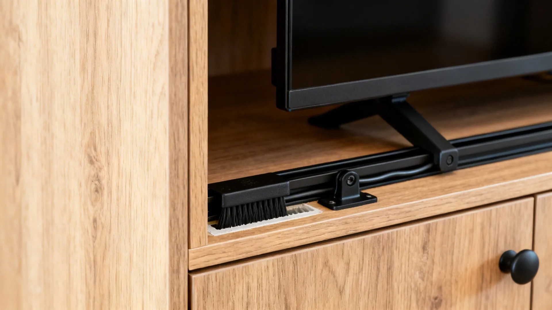 Macro of pocket door track, ventilation gap, and brush grommet in a TV cabinet niche.