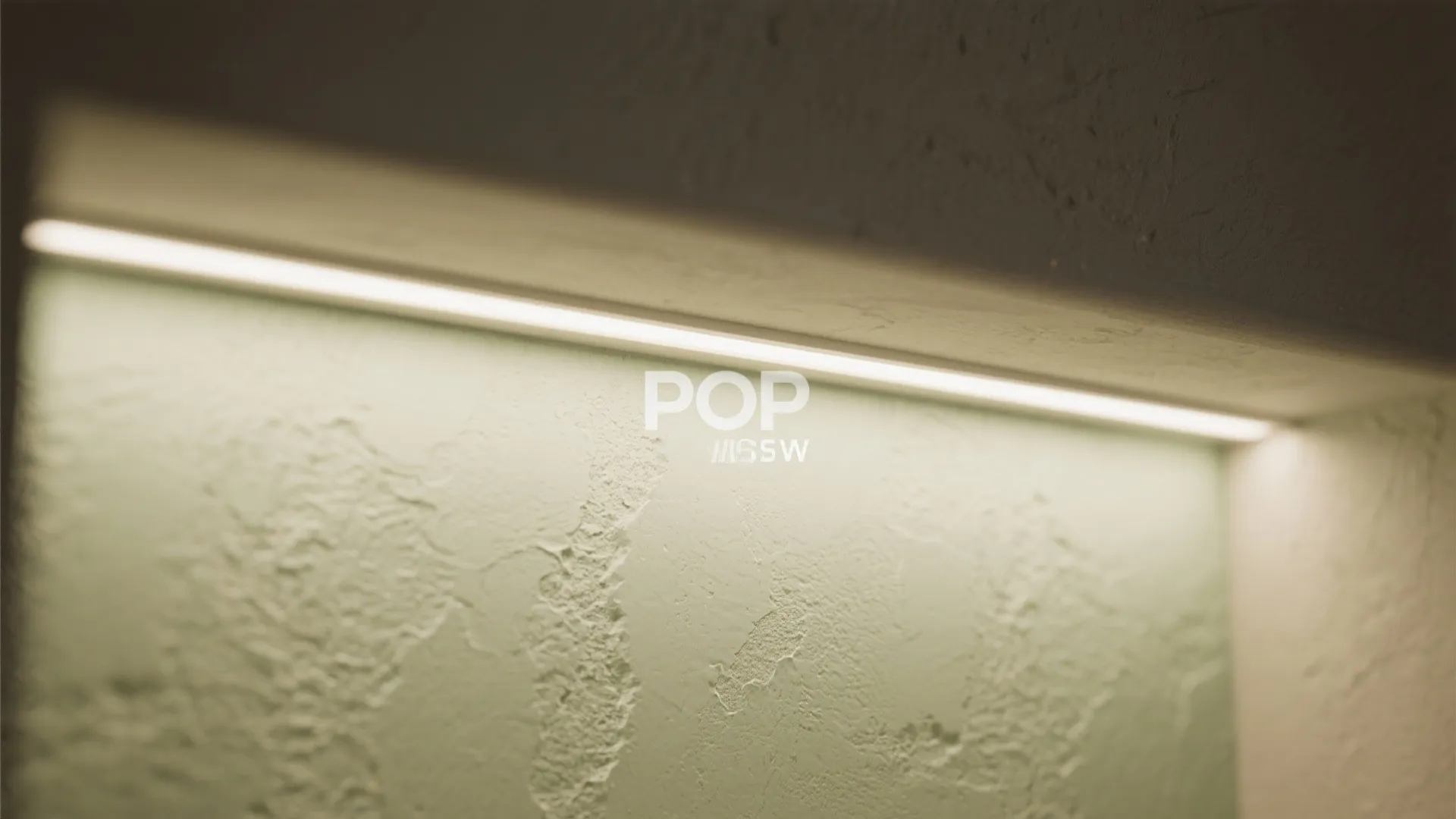Close up of linear light fixture hidden inside a textured green wall with soft warm lighting