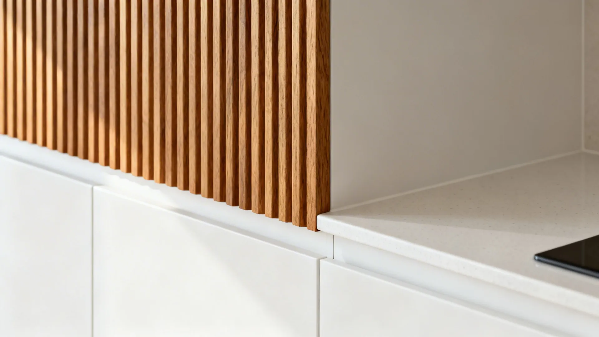Macro of ribbed oak accent next to matte white cabinetry and quartz worktop.