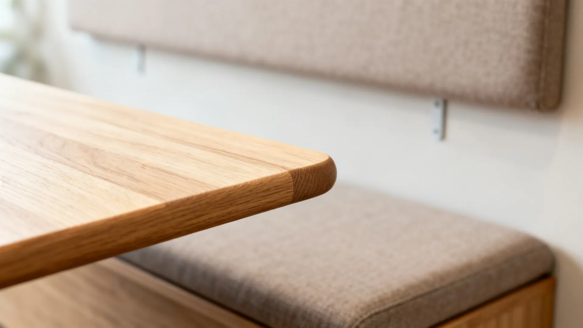 Close-up of a light oak tabletop edge with soft radius and bench cushion texture.