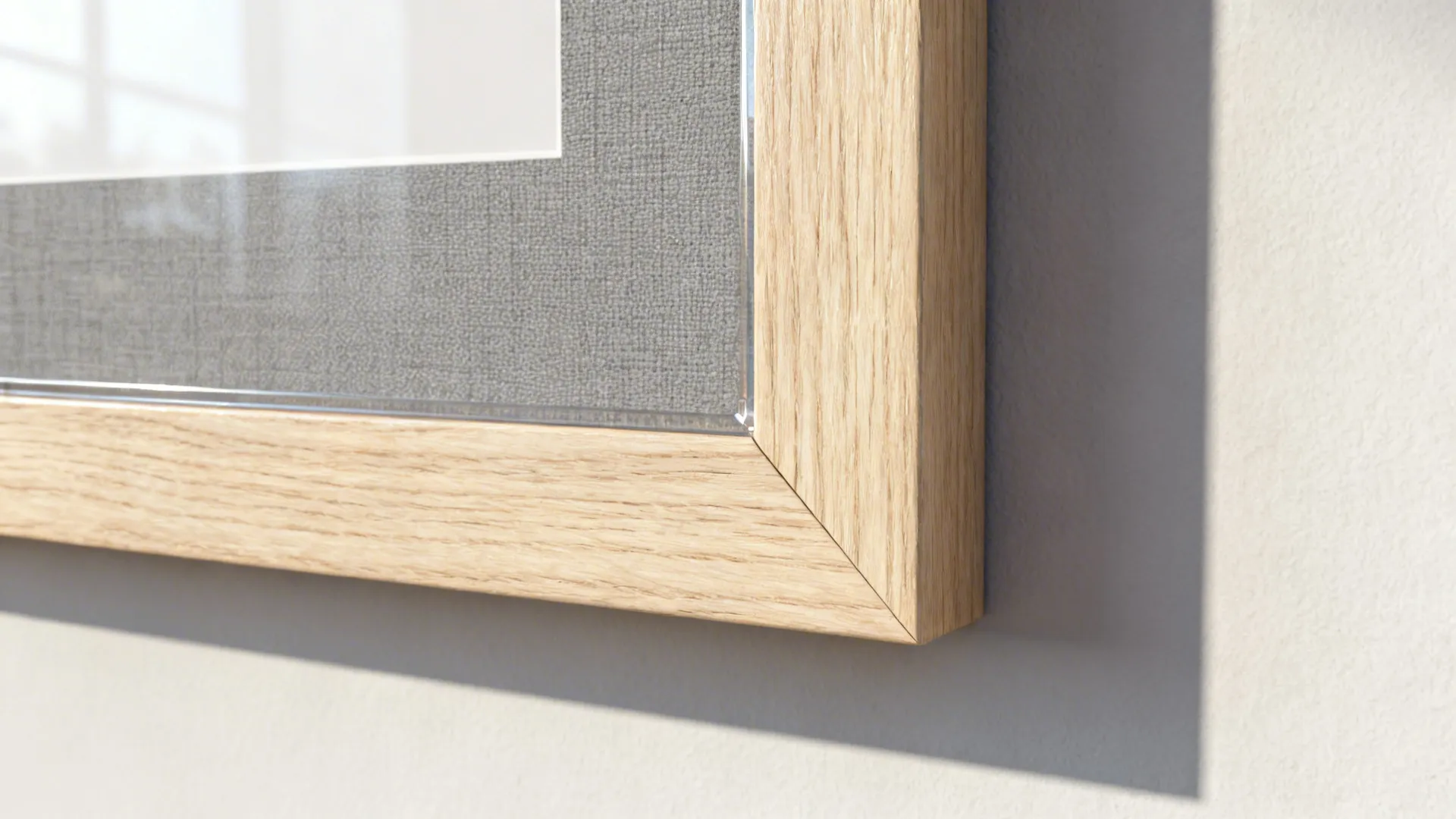 Close up of a light wood picture frame corner with grey matting on a plain wall