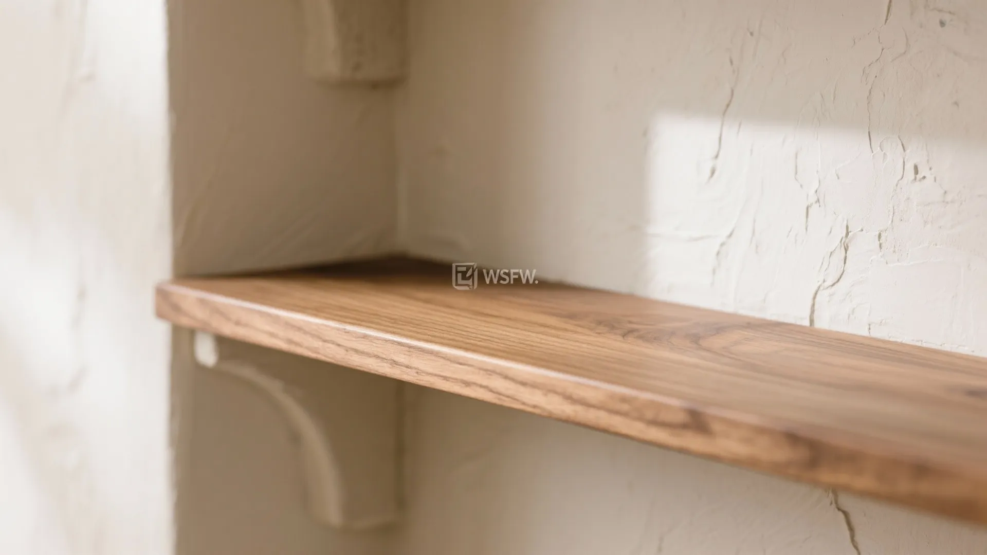 Close up of a smooth wooden shelf mounted on a textured white interior wall panel