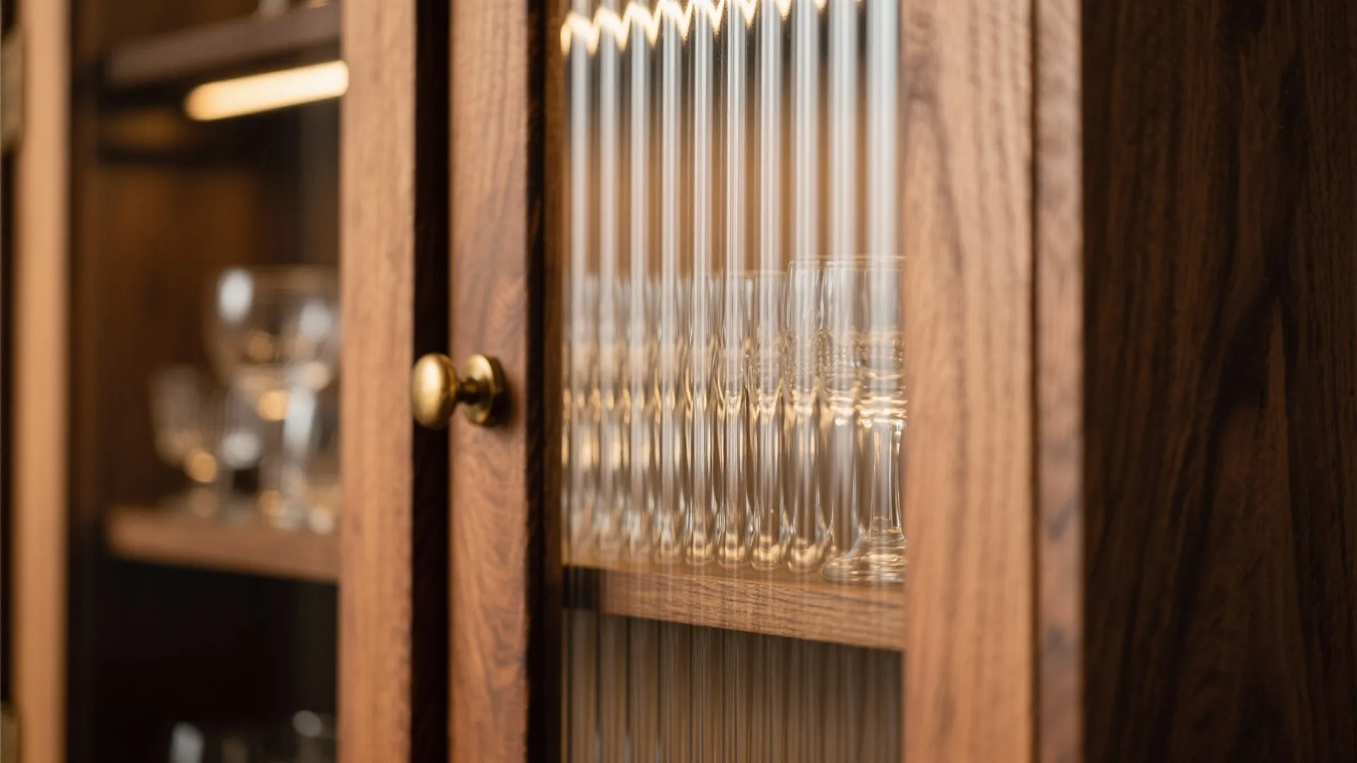 Close up of a wooden storage cabinet with glass doors showing glass cups stored inside