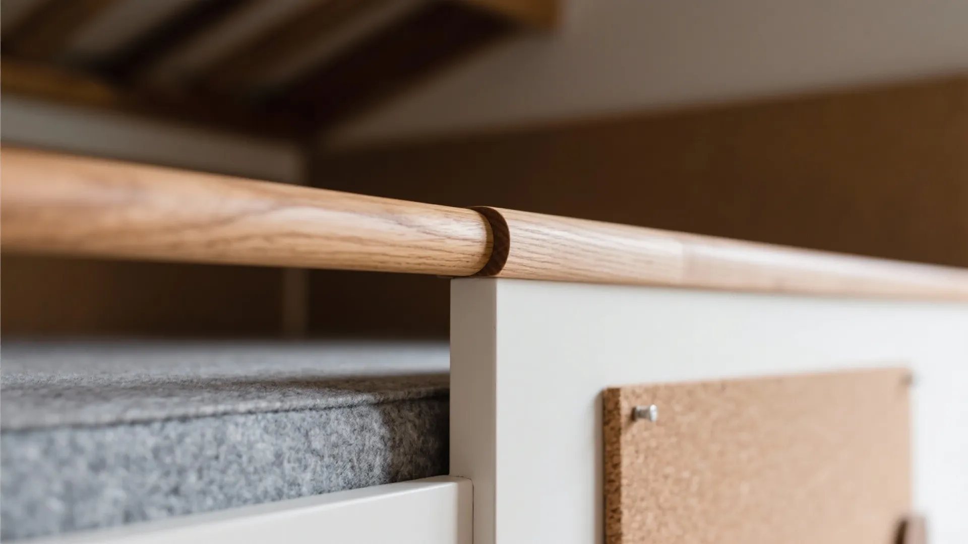 Macro of rounded oak guardrail with hardwax oil finish beside felt and cork textures.