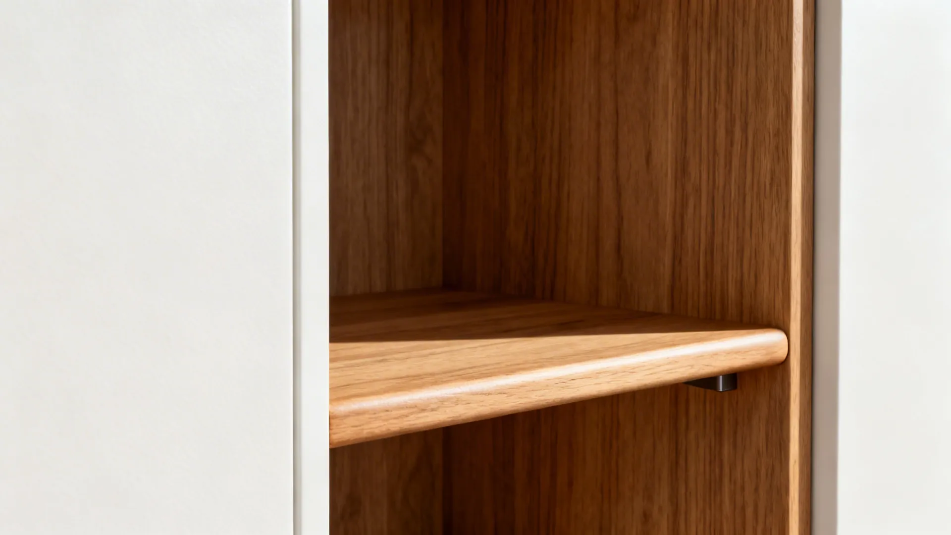 Close-up of a sealed oak shelf with concealed bracket against white cabinetry.