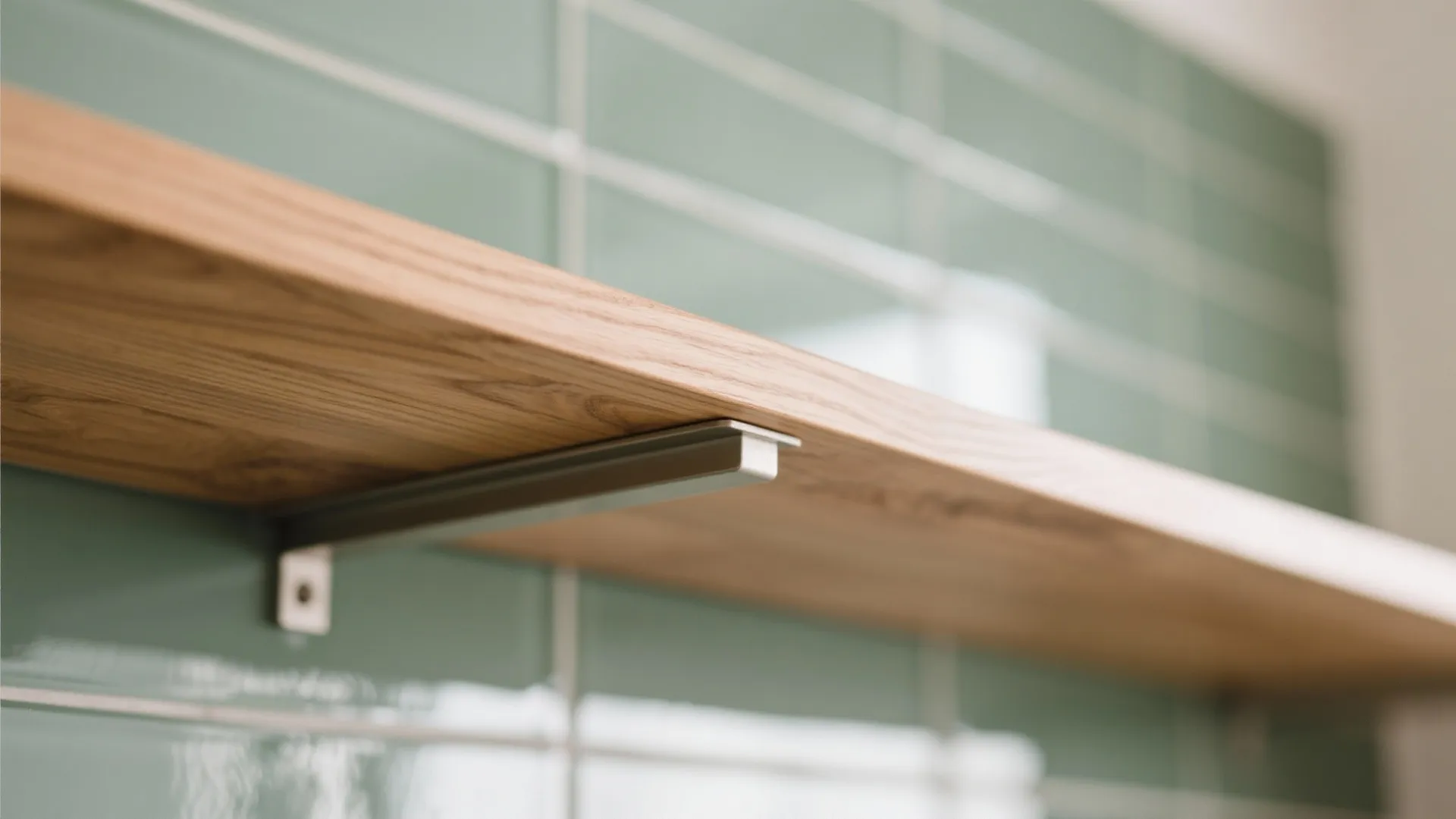 Close up shot of a light wood floating shelf mounted on a green tiled wall