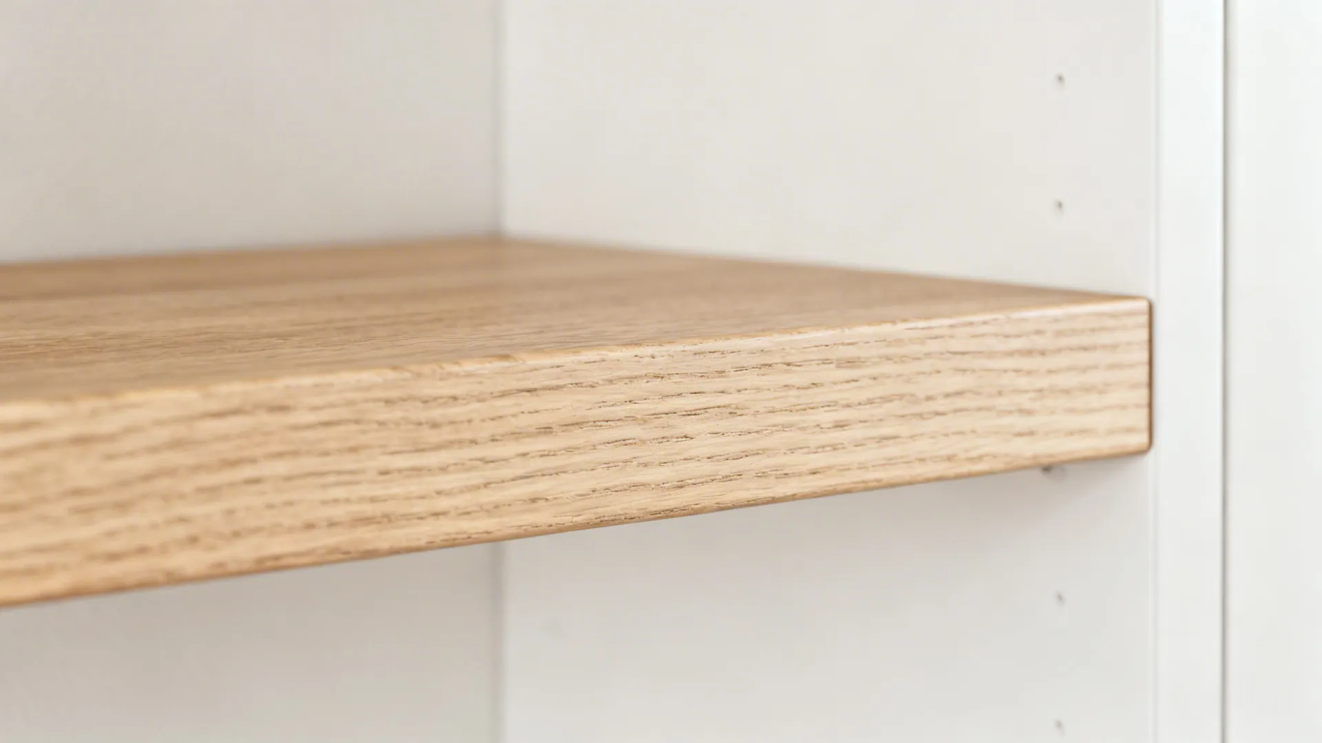 Detailed view of a light brown wood shelf installed inside a bright white wall cabinet