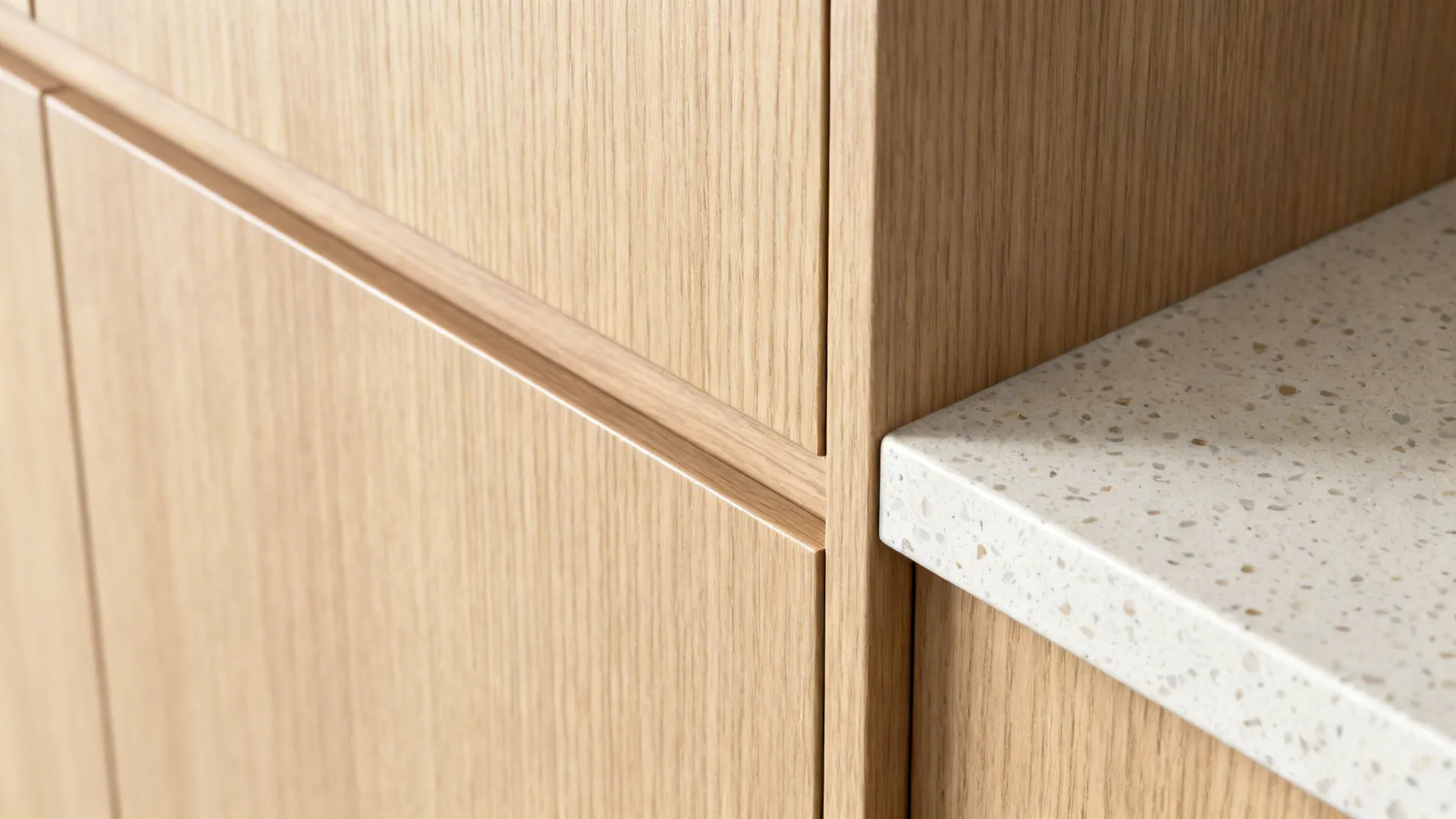 Macro of light rift oak grain beside a pale terrazzo counter with fine aggregate.