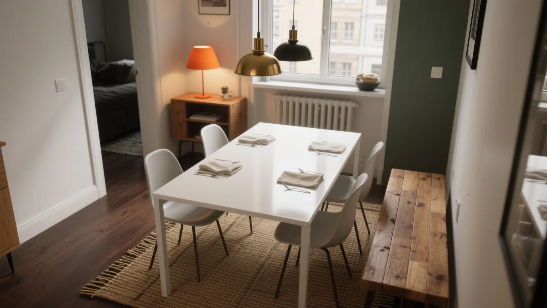 White dining table with four white chairs on brown rug with two hanging ceiling lights