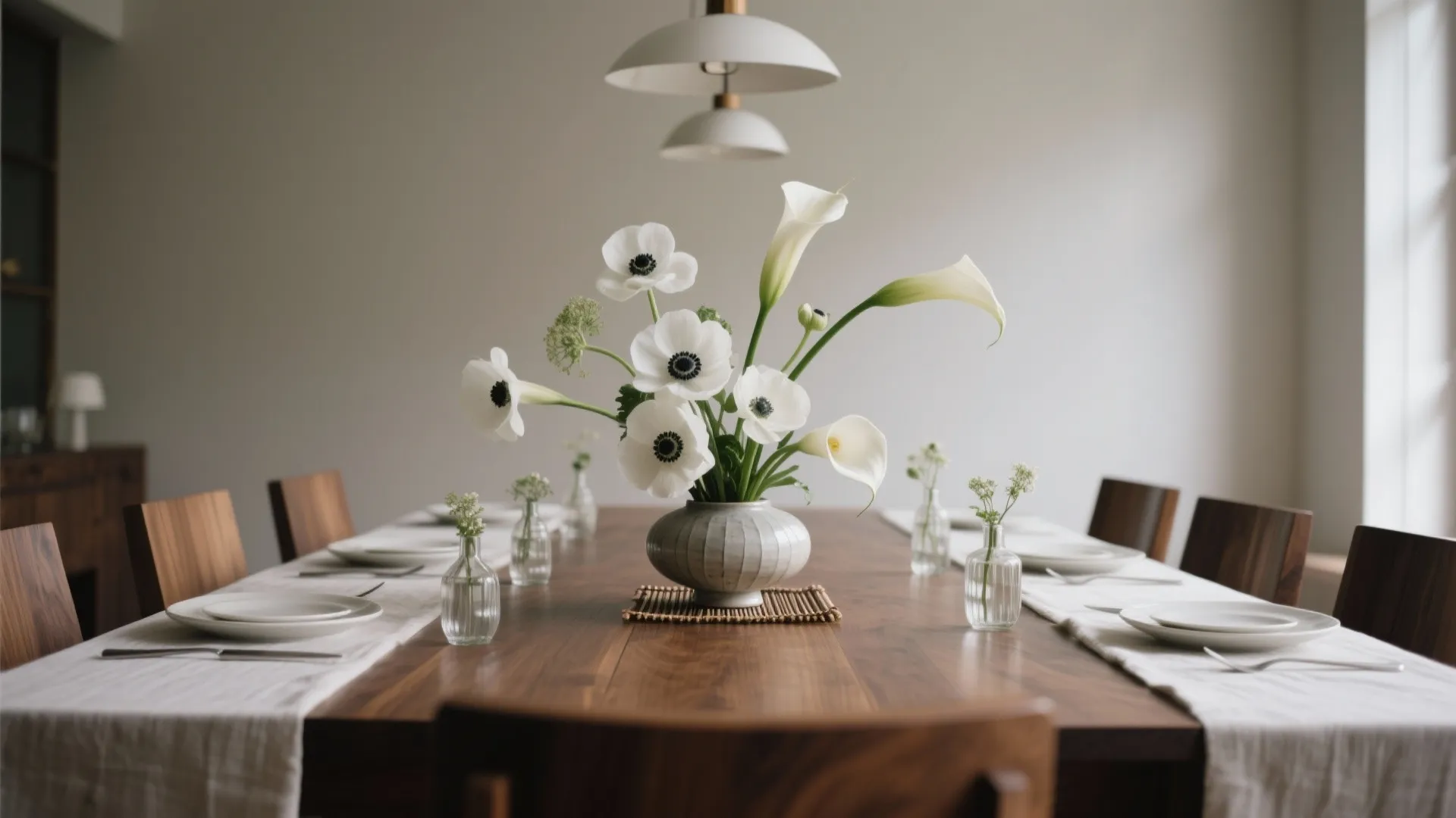 Modern dining room featuring a wooden table with white flower vases and white ceiling lights
