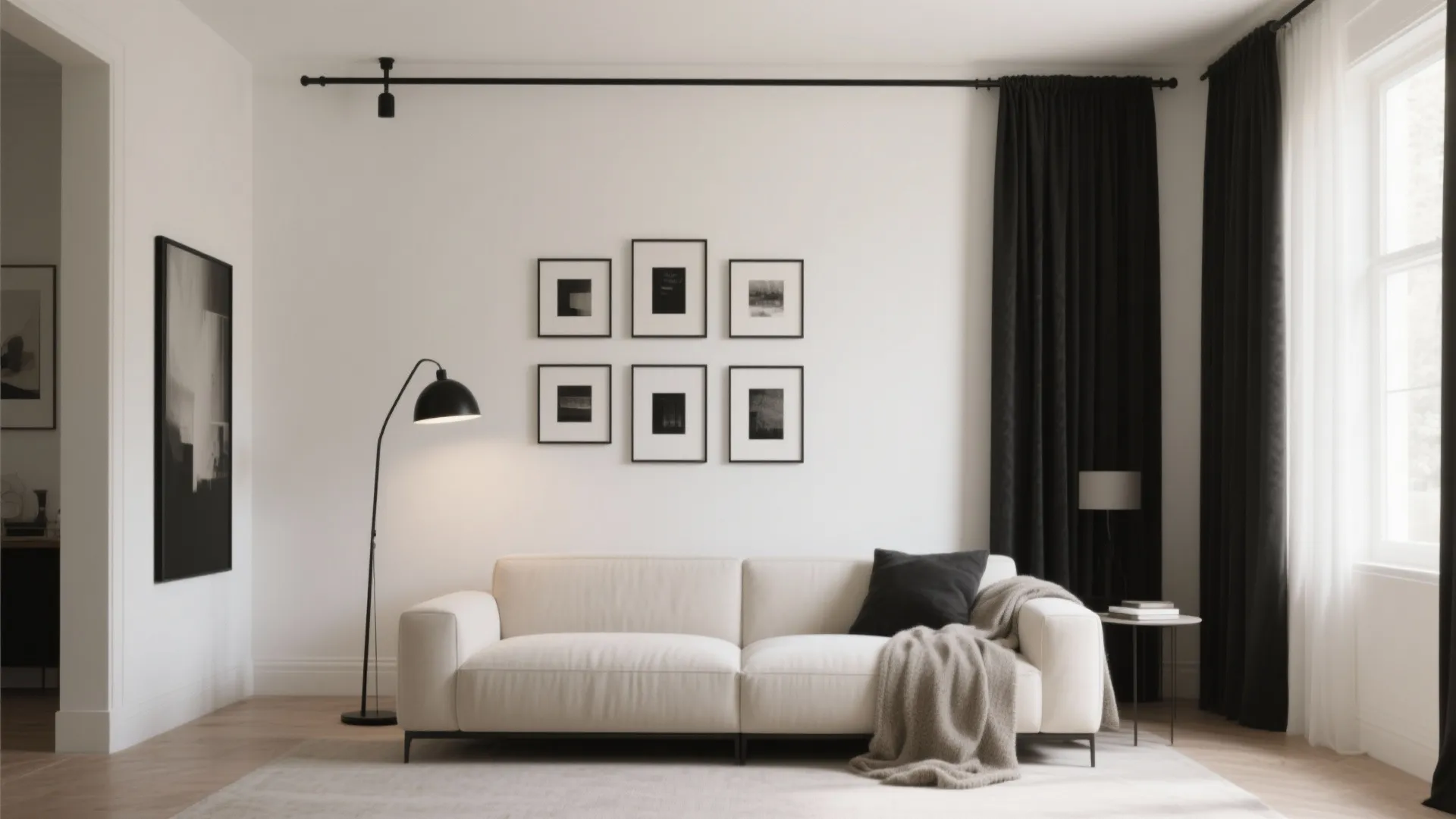 Modern white sofa with black pillows and throw blanket in minimalist living room with gallery