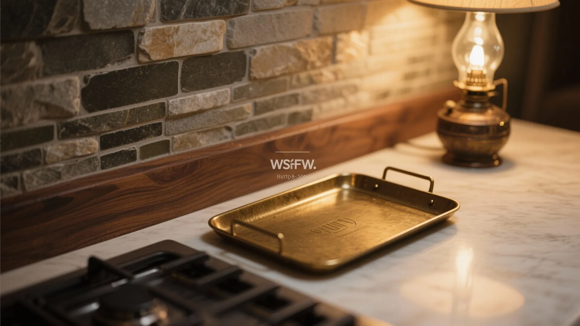 Brass serving tray on marble kitchen counter near a warm table lamp and stone wall