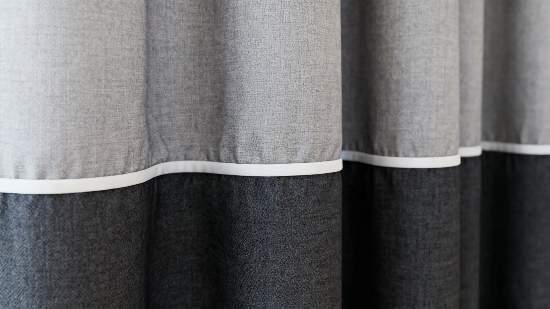 Close-up of ombre grey curtains with a white trim hem