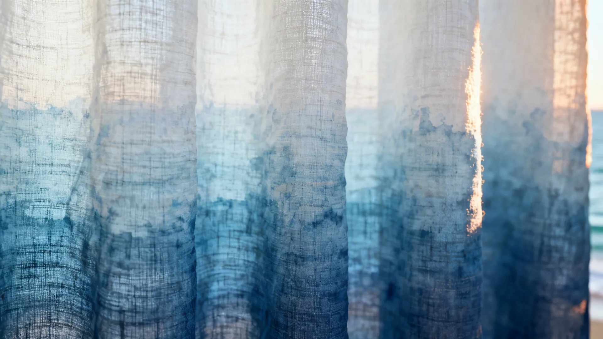 Close-up of soft ombre blue linen curtain showing gradient to white and visible fabric texture.