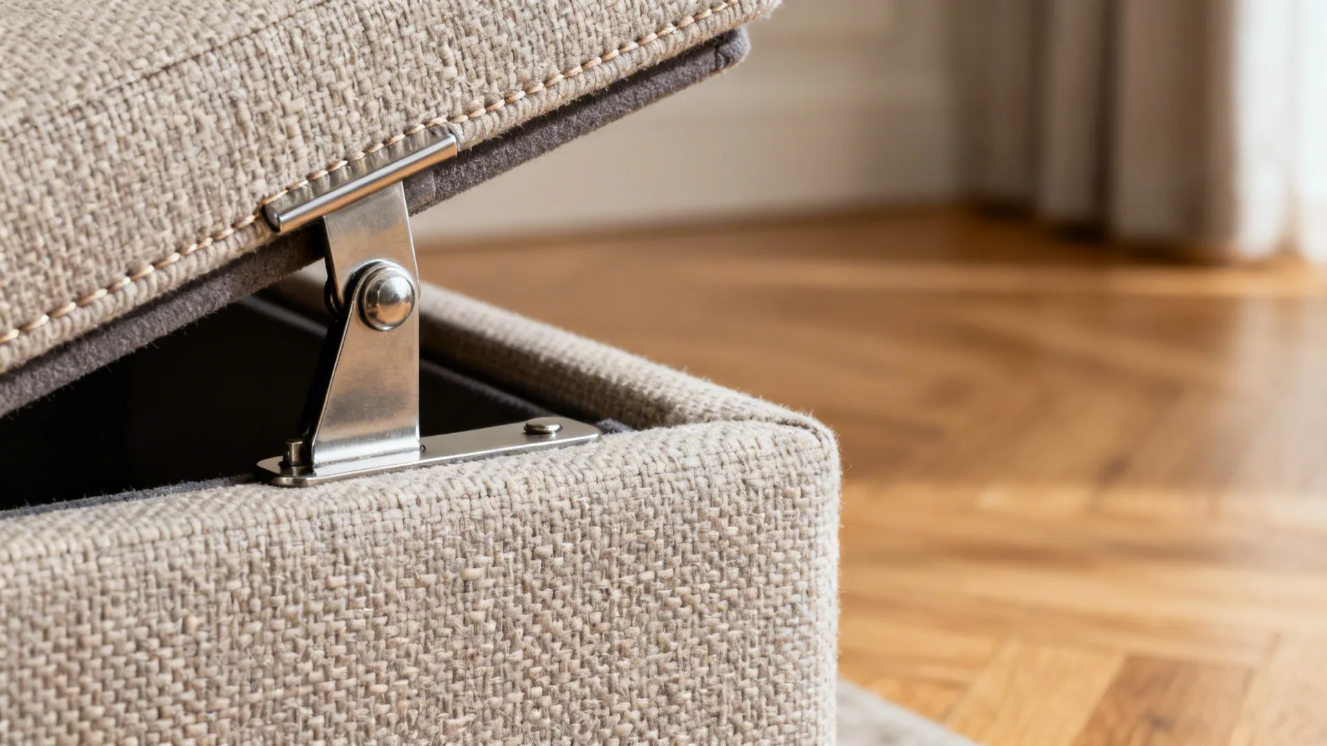 Close-up of a lift-top ottoman hinge and textured fabric in soft light.