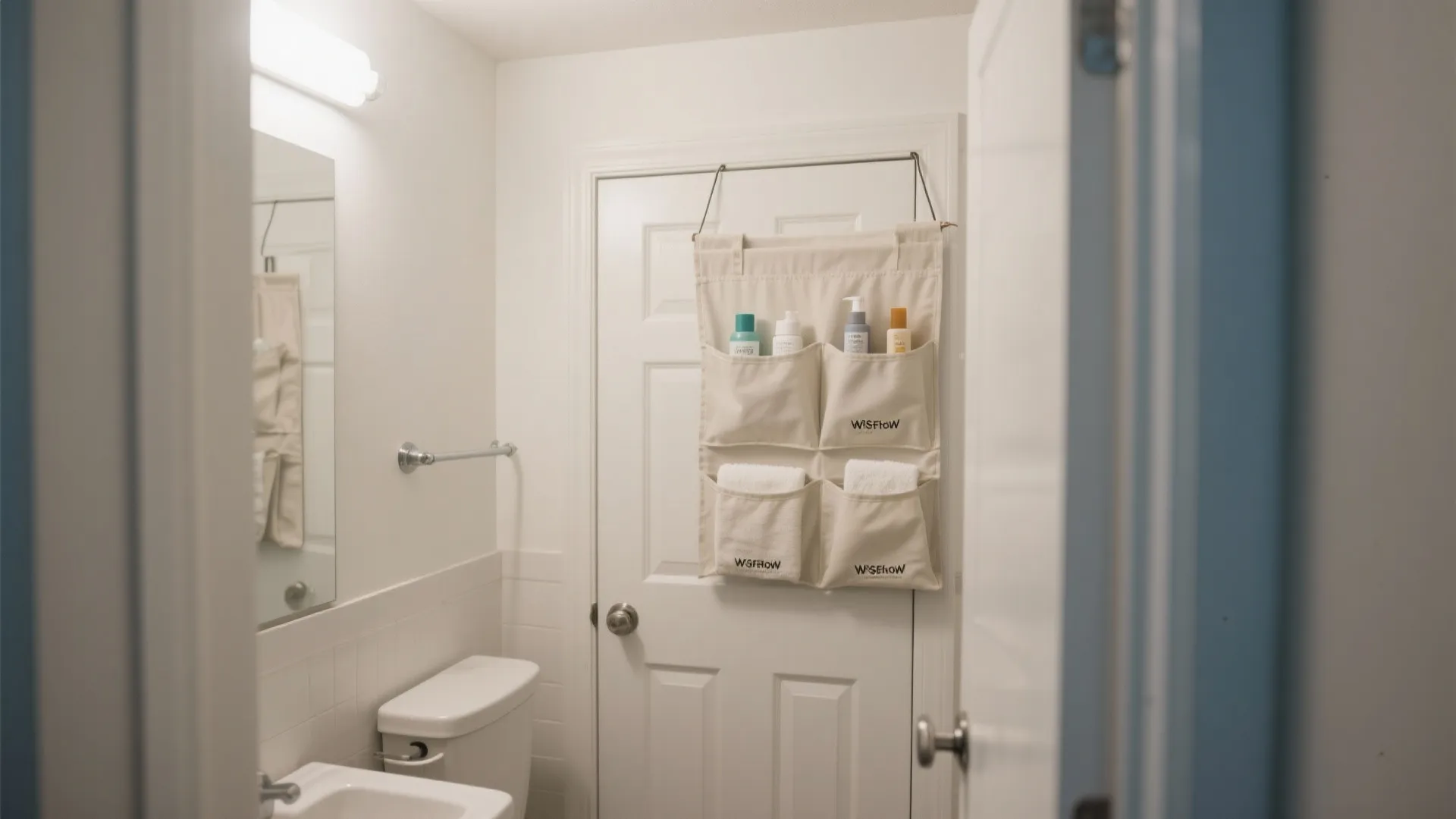 Beige hanging door organizer with four pockets holding toiletries and towels in a white bathroom