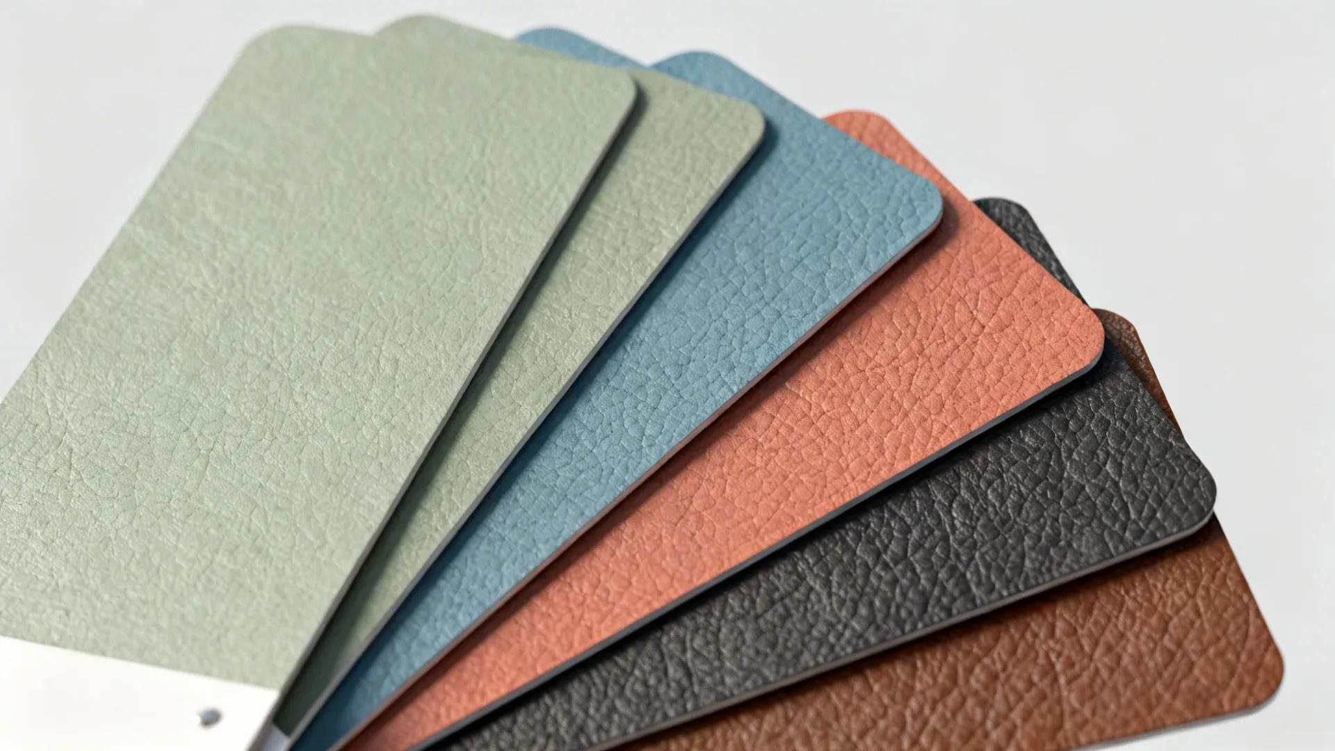 Paint chip samples including neutrals, sage, dusty blue, terracotta and charcoal beside a brown leather swatch.