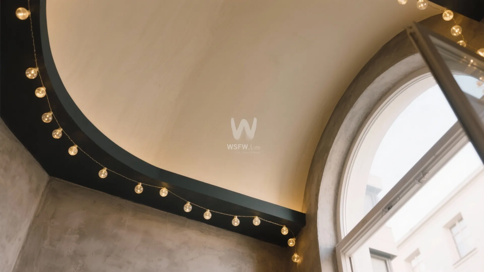 Interior room with a curved white ceiling and small round string lights on a dark beam