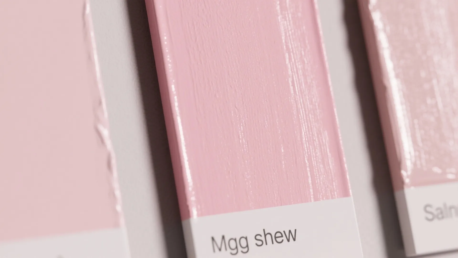 Close up of pink paint color swatches with different names on a white wall background