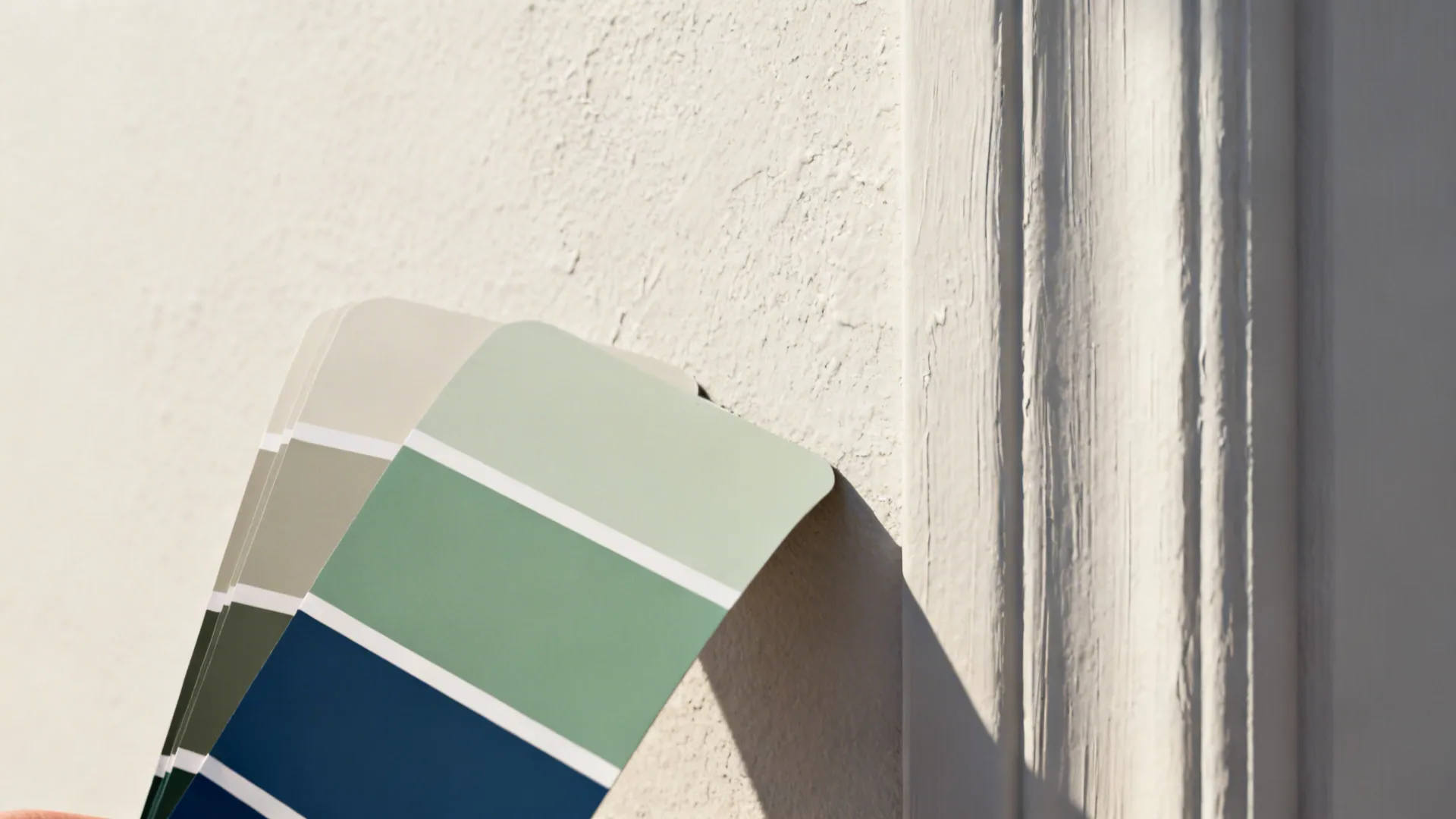 Macro view of painted wall texture next to a paint sample card with neutral and deep blue options.
