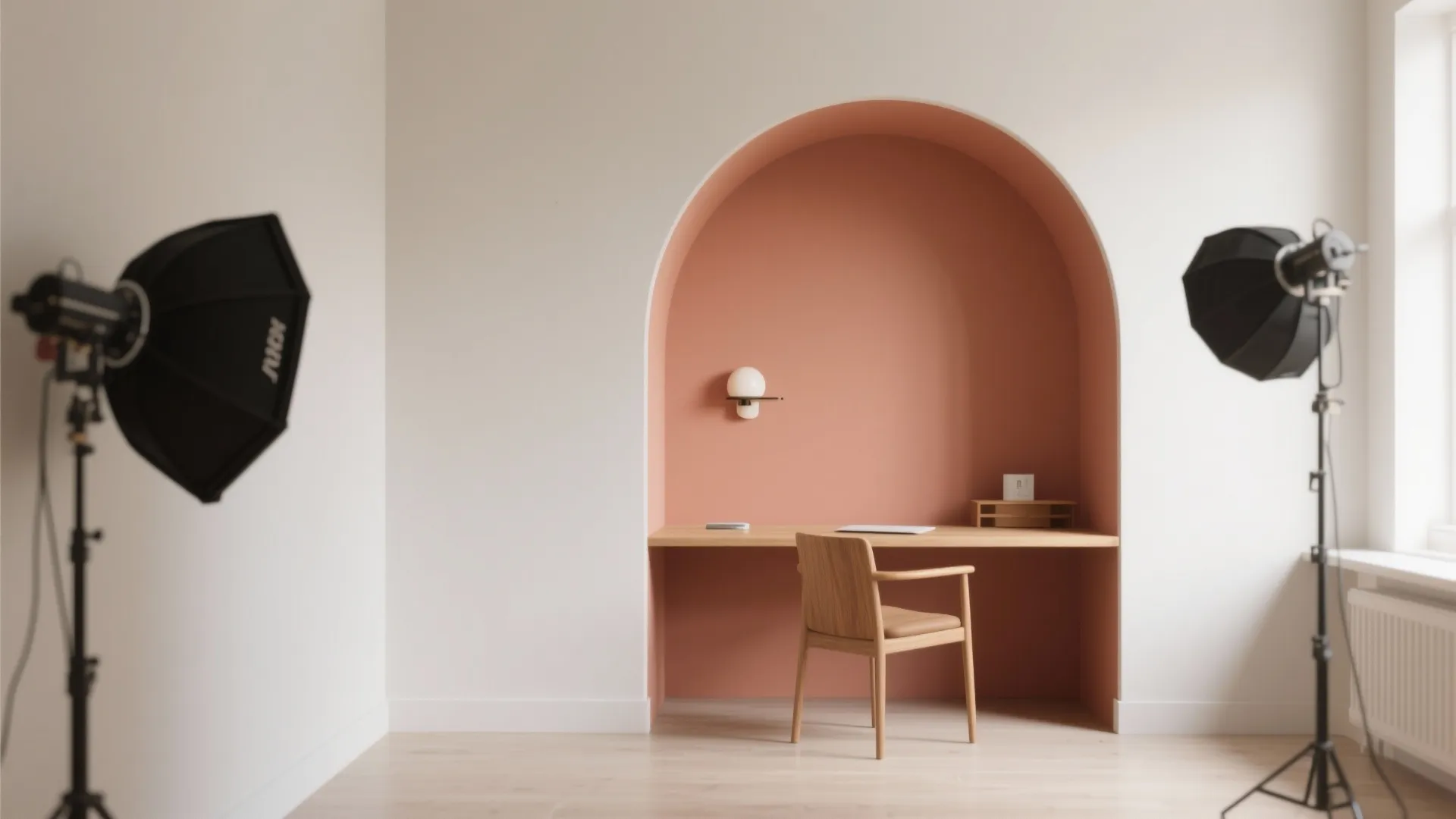 Minimalist home office with a wooden desk inside a pink painted wall arch and chair