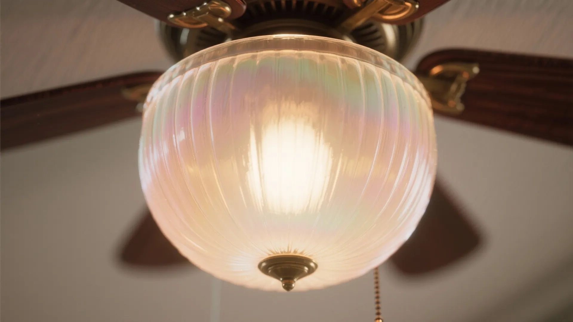 Close up of a ceiling light with iridescent glass bowl attached to a wooden fan