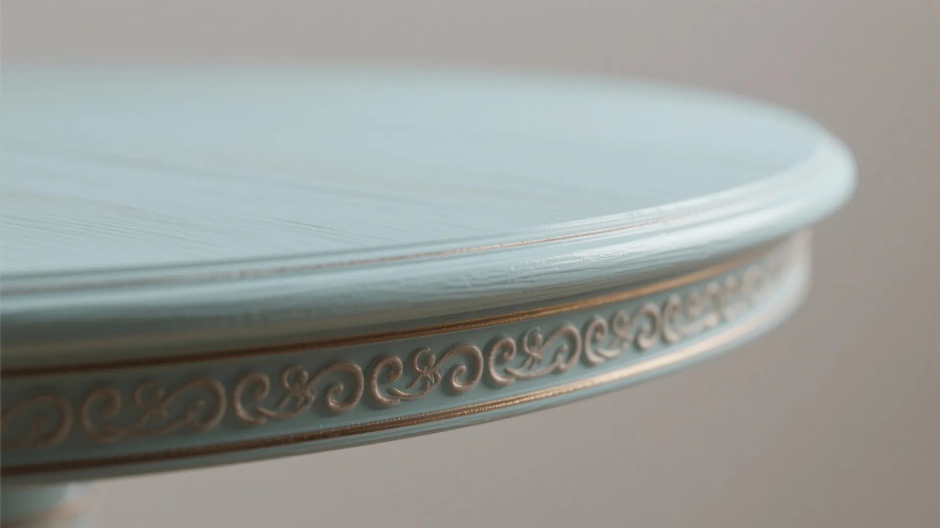 Close up view of light blue round table edge with decorative carved pattern and details