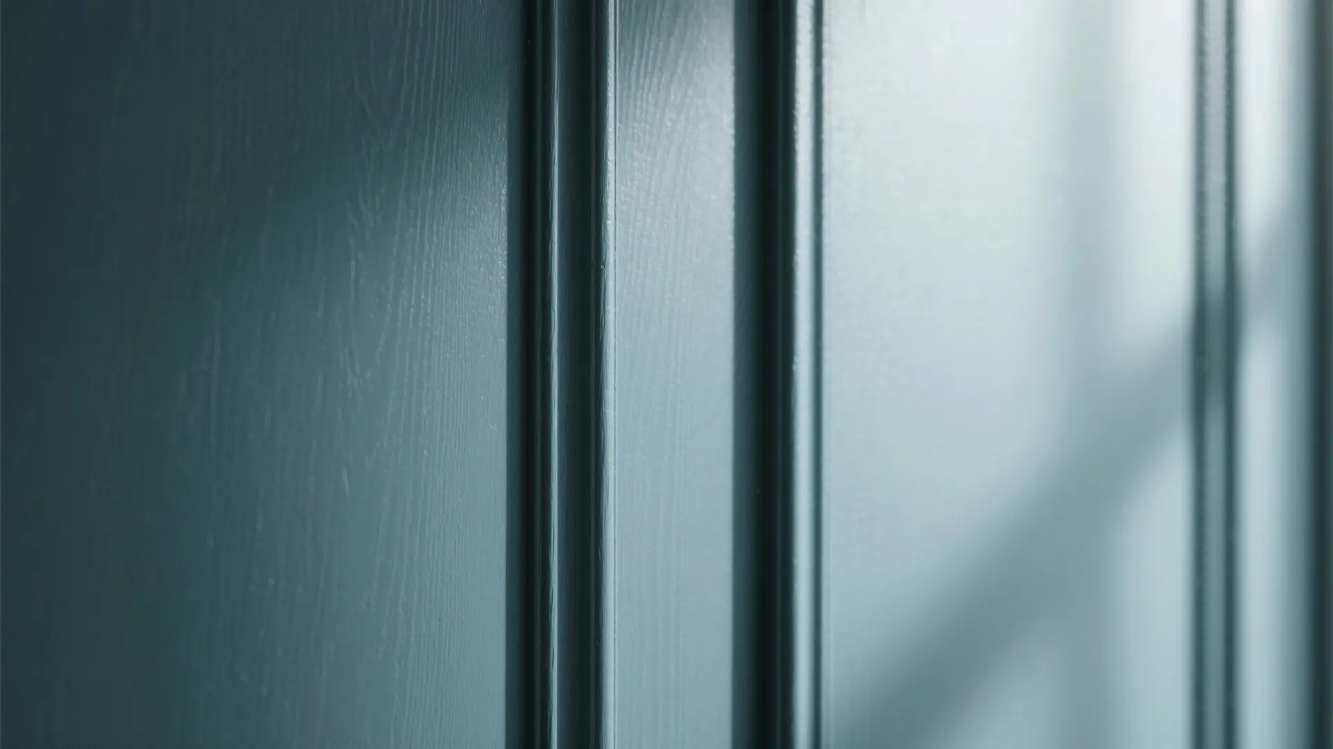 Close up view of dark teal blue wall panel with vertical lines and natural light