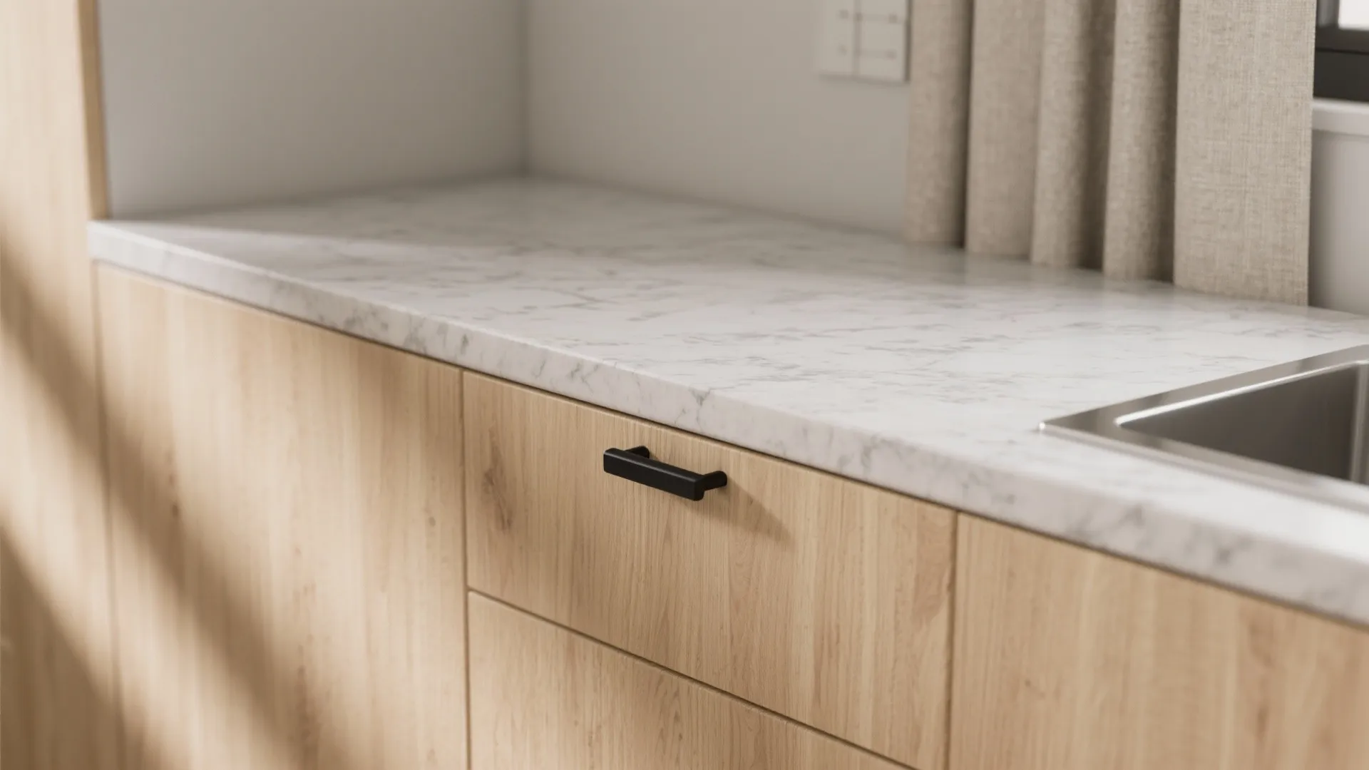 Close up of marble kitchen counter top with wooden cabinet black handle and metal water sink