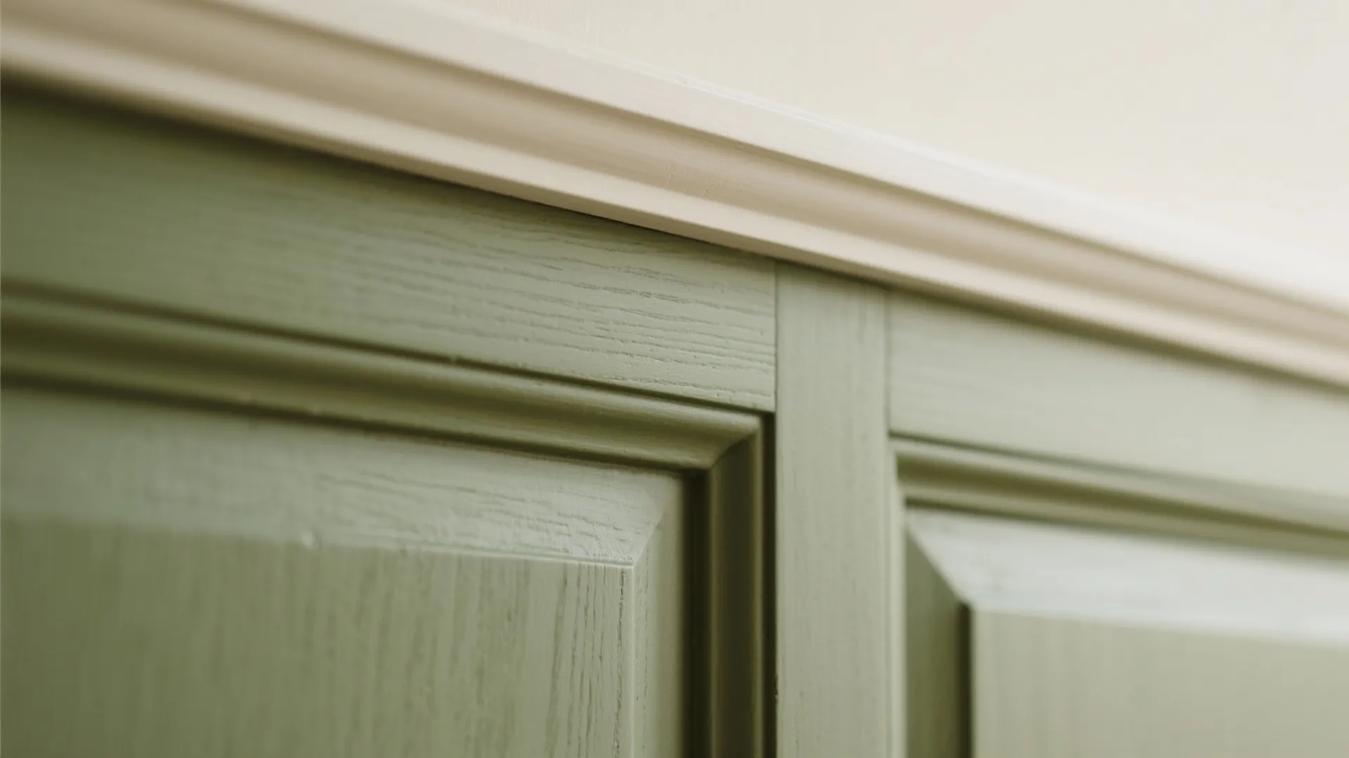 Close up of green wooden wall panels with a white decorative trim at the top