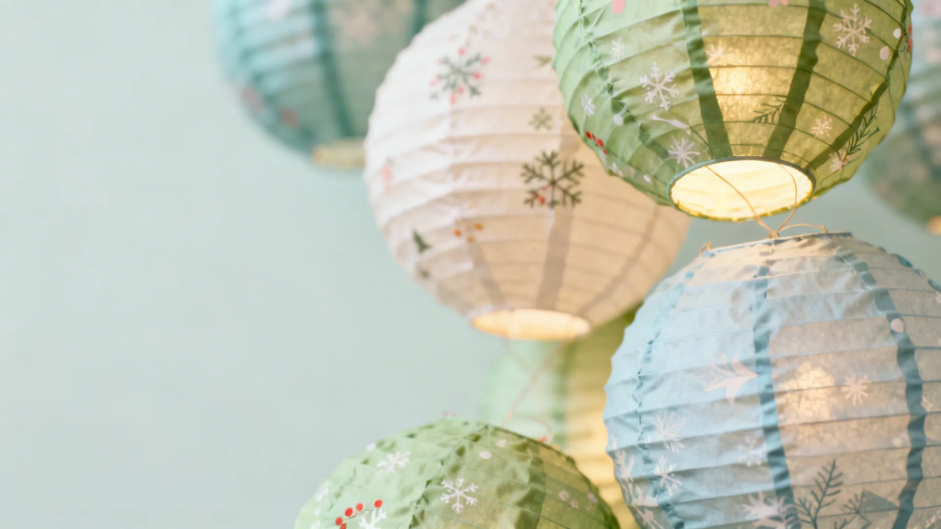 Paper and fabric lanterns emitting a soft even glow in a cozy corner, showcasing delicate textures.