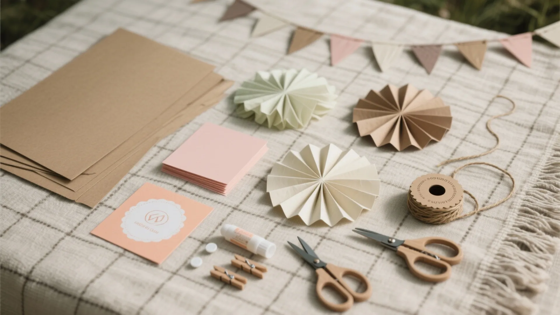 Craft supplies including brown paper sheets scissors glue twine and colorful paper fans on checkered cloth