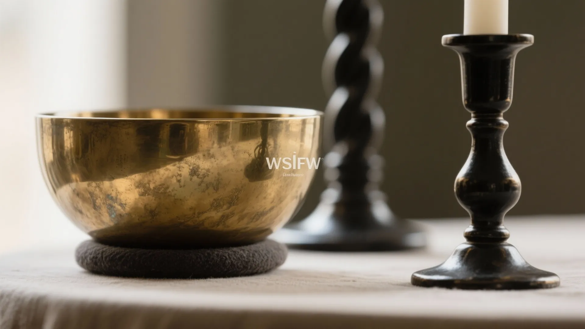 Macro of patinated brass bowl and blackened steel candlestick showing finish contrast.
