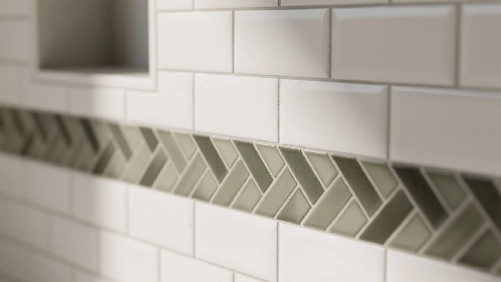Close up of white wall tiles with a green patterned decorative strip in a bathroom