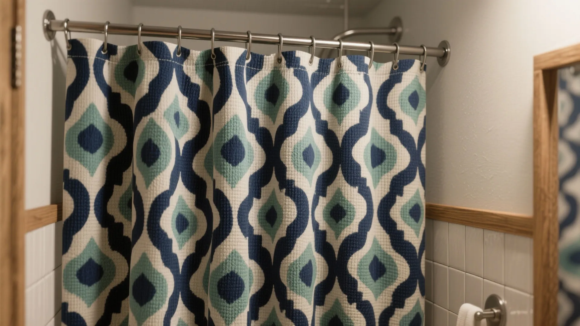 Blue and white patterned bathroom shower curtain hanging on a metal rod with silver hooks