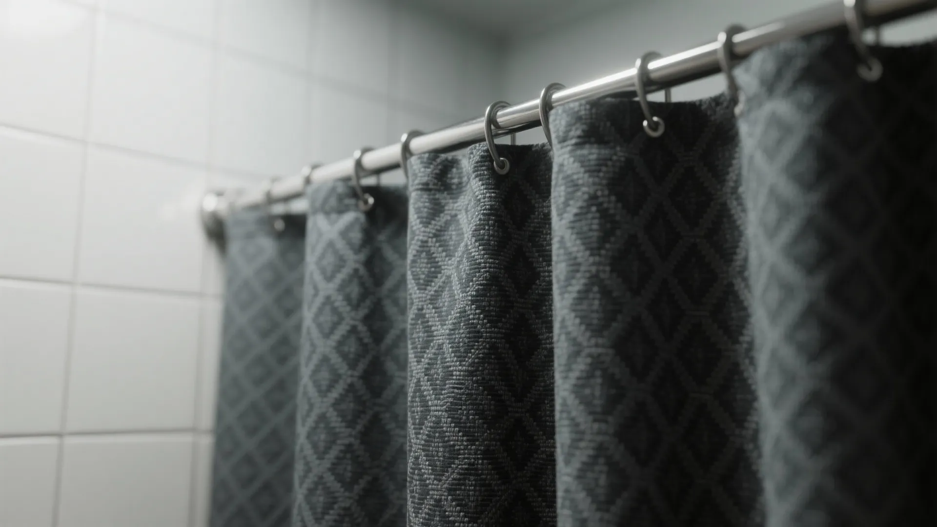 Close up of a dark grey patterned curtain hanging on a metal rod with rings
